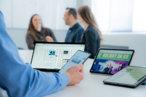 Benutzer mit mehreren Mobilen Geräte am Schreibtisch im Hintergrund Kollegen