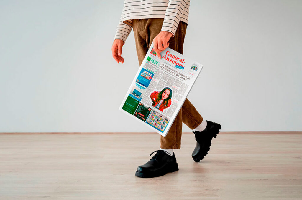 Eine Person geht und hält die Wochenzeitung General-Anzeiger in der Hand.