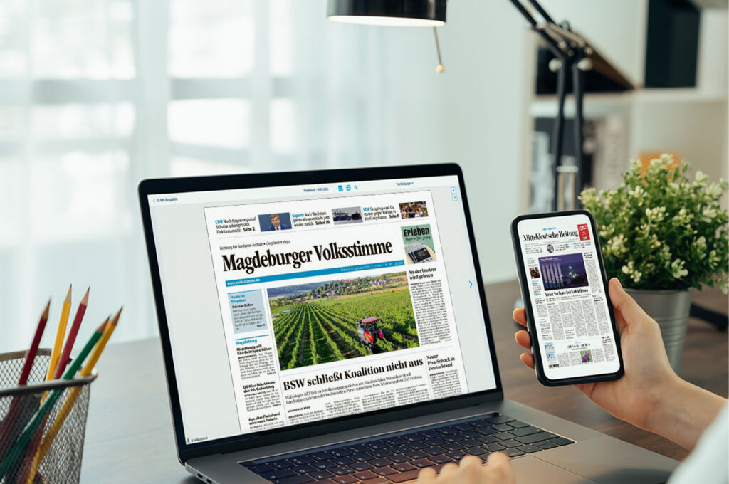 Laptop und Smartphone mit digitalen Zeitungsansichten der "Magdeburger Volksstimme2 und der "Mitteldeutschen Zeitung" auf einem Schreibtisch. ©Mockup AdobeStock, Inhalt Mediengruppe Mitteldeutschland