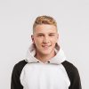 Porträt einer jungen Person mit kurzen hellen Haaren in einem weiß-schwarzen Kapuzenpullover vor einem hellgrauen Hintergrund. Die Person blickt direkt in die Kamera. ©AdobeStock